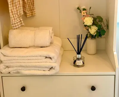 a pile of towels on a cabinet with a vase of flowers at Little Peterville in St. Agnes