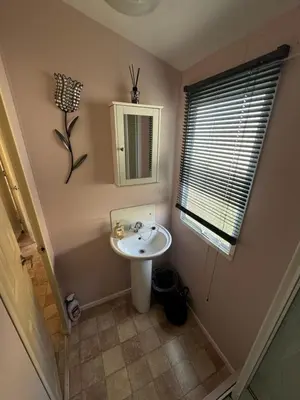 a small bathroom with a sink and a mirror at Meadow & Tide in St Merryn