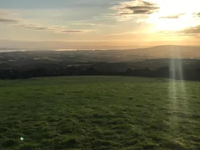 a green field with the sun shining on the horizon at Phoenix Farm Shepherds Hut,Minions, Cornwall in Liskeard