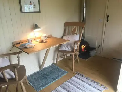 a wooden table with two chairs and a fireplace at Phoenix Farm Shepherds Hut,Minions, Cornwall in Liskeard