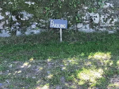 a parking sign in the grass next to a stone wall at Phoenix Farm Shepherds Hut,Minions, Cornwall in Liskeard