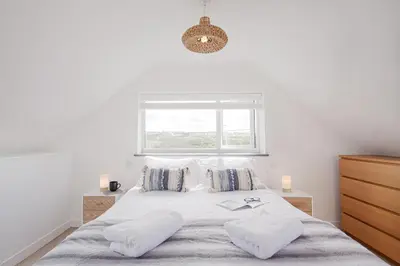 a white bedroom with a large bed with a window at One bed spectacular ocean views, walk to the beach in Truro