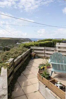 a blue chair sitting on a patio with flowers at One bed spectacular ocean views, walk to the beach in Truro