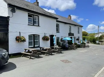 a white building with picnic tables in front of it at The New Inn in Veryan
