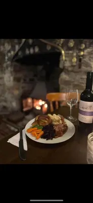 a plate of food on a table with a bottle of wine at The New Inn in Veryan
