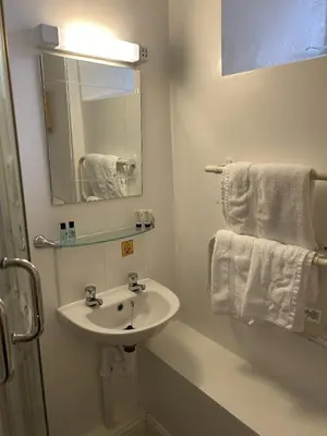 a bathroom with a sink and a mirror and towels at The New Inn in Veryan