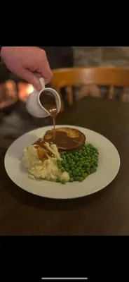 a plate of food with mashed potatoes and peas with a spoon at The New Inn in Veryan