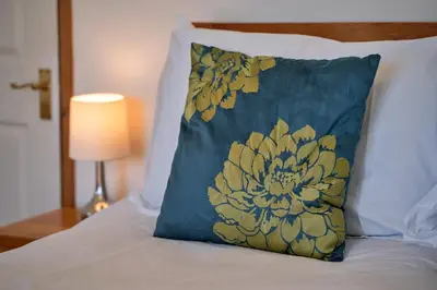 a blue pillow with a yellow flower on a bed at Finest Retreats - Chy Merthen East in Marazion