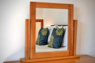 a mirror on a table with a bed with pillows at Finest Retreats - Chy Merthen East in Marazion