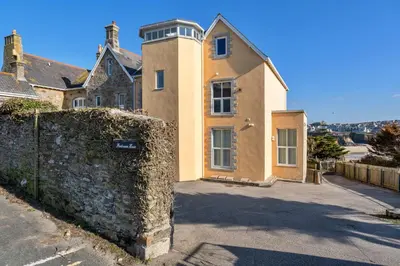 a house with a stone wall and a fence at Finest Retreats - Tidal Shores in Newquay