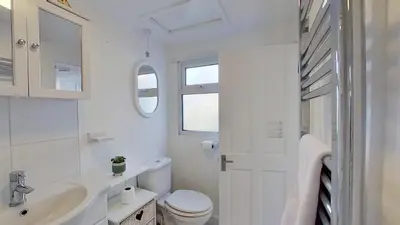 a white bathroom with a toilet and a sink at B12 Branksome, Riviere Towans in Hayle