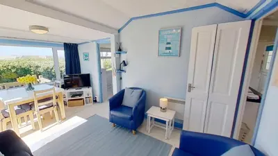 a living room with a blue chair and a table at B12 Branksome, Riviere Towans in Hayle