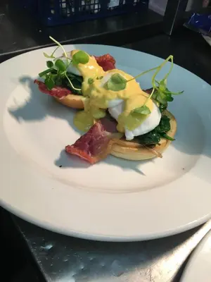 a white plate with a breakfast sandwich with cheese and greens at The Ship Inn Fowey in Fowey