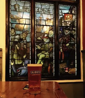 a glass sitting on a table in front of a stained glass window at The Ship Inn Fowey in Fowey
