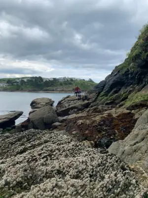 two people standing on the rocks near the water at The Ship Inn Fowey in Fowey