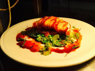 a white plate with a piece of meat and vegetables at The Ship Inn Fowey in Fowey