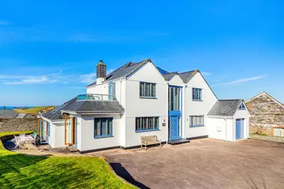 a large white house with a blue door at 5 Bed in Trevone oc-s30762 in Padstow