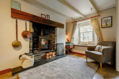 a living room with a fireplace and a chair at 2 Bed in St. Minver oc-p27580 in Saint Minver