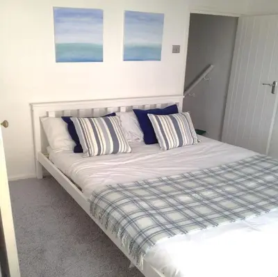 a bed with blue and white pillows in a bedroom at Ideally located cottage in Downalong St Ives in St Ives
