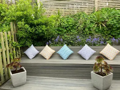 a row of pillows sitting on a bench with plants at Ideally located cottage in Downalong St Ives in St Ives