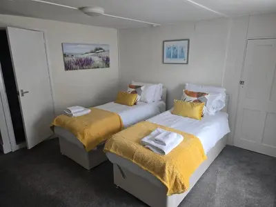 two beds in a room with yellow pillows at Ring O Bells in St. Issey