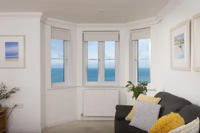 a living room with windows and a couch at Bay View, Compass Point, Sea Views, Free Parking and WiFi in Carbis Bay