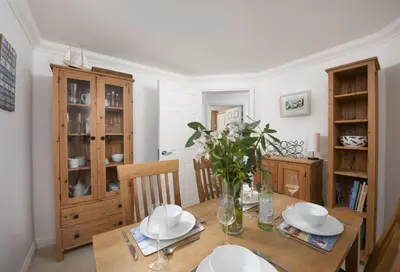 a dining room with a table with plates and flowers on it at Bay View, Compass Point, Sea Views, Free Parking and WiFi in Carbis Bay