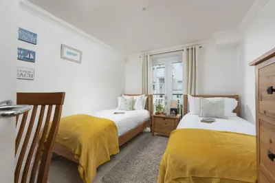 a bedroom with two beds with yellow sheets and a window at Bay View, Compass Point, Sea Views, Free Parking and WiFi in Carbis Bay