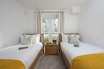 two beds in a room with a window at Bay View, Compass Point, Sea Views, Free Parking and WiFi in Carbis Bay