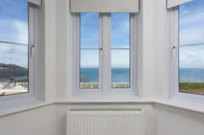 a white room with three windows and a radiator at Bay View, Compass Point, Sea Views, Free Parking and WiFi in Carbis Bay