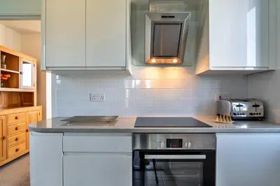 a kitchen with white cabinets and a stove top oven at Finest Retreats - Chy Merthen House in Marazion