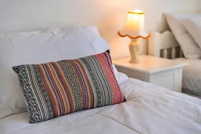 a pillow on a bed with a lamp on a table at Finest Retreats - Chy Merthen House in Marazion