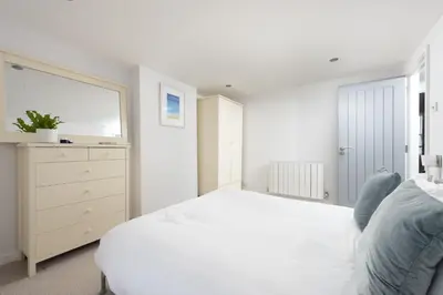 a white bedroom with a white bed and a dresser at Salubrious Cottage, St Ives in St Ives