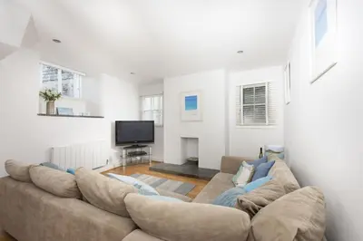 a living room with a large couch and a tv at Salubrious Cottage, St Ives in St Ives