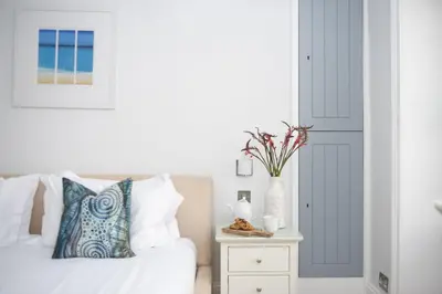 a bedroom with a bed and a table with a vase on it at Serendipity Cottage, St Ives in St Ives