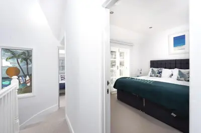 a bedroom with a bed with a green blanket at Serendipity Cottage, St Ives in St Ives
