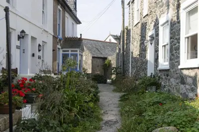 a path between two houses with flowers and plants at Serendipity Cottage, St Ives in St Ives