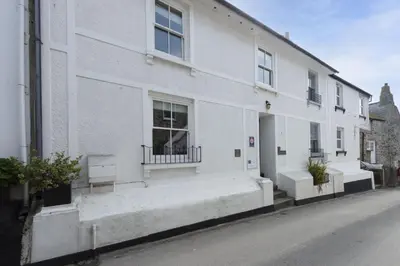 a white building with two windows and a street at Serendipity Cottage, St Ives in St Ives