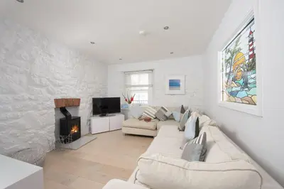 a white living room with a couch and a fireplace at Serendipity Cottage, St Ives in St Ives