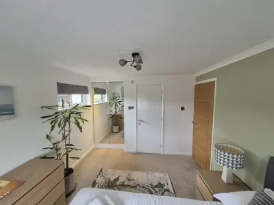 a bedroom with a bed and a desk with a plant at Whispering Waters in Newquay