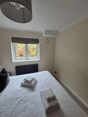 a bedroom with a large white bed with towels on it at Whispering Waters in Newquay