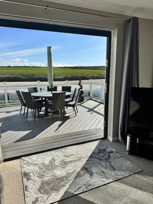 a dining room with a table and chairs on a deck at Whispering Waters in Newquay