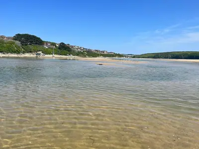 a body of water with a beach in the background at Whispering Waters in Newquay
