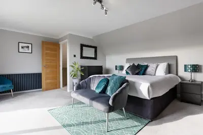 a bedroom with a king sized bed and a chair at Whispering Waters in Newquay