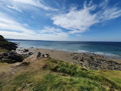 a beach with rocks and the ocean on a cloudy day at Cornwall Luxury Hot Tub Huts in Camelford
