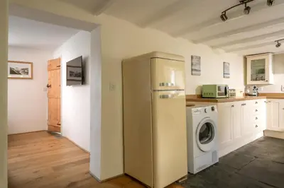 a kitchen with a refrigerator and a washing machine at 1 Rock Cottages in Treknow