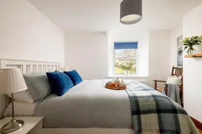 a bedroom with a bed with blue pillows at 1 Rock Cottages in Treknow