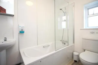 a white bathroom with a shower and a toilet at ON THE BEACH holiday home in St Merryn