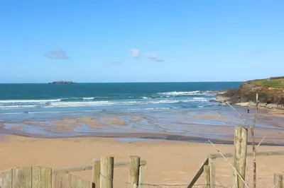 a beach with a fence and the ocean at ON THE BEACH holiday home in St Merryn