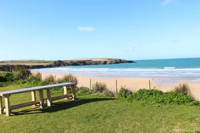 a bench sitting on the side of a beach at ON THE BEACH holiday home in St Merryn